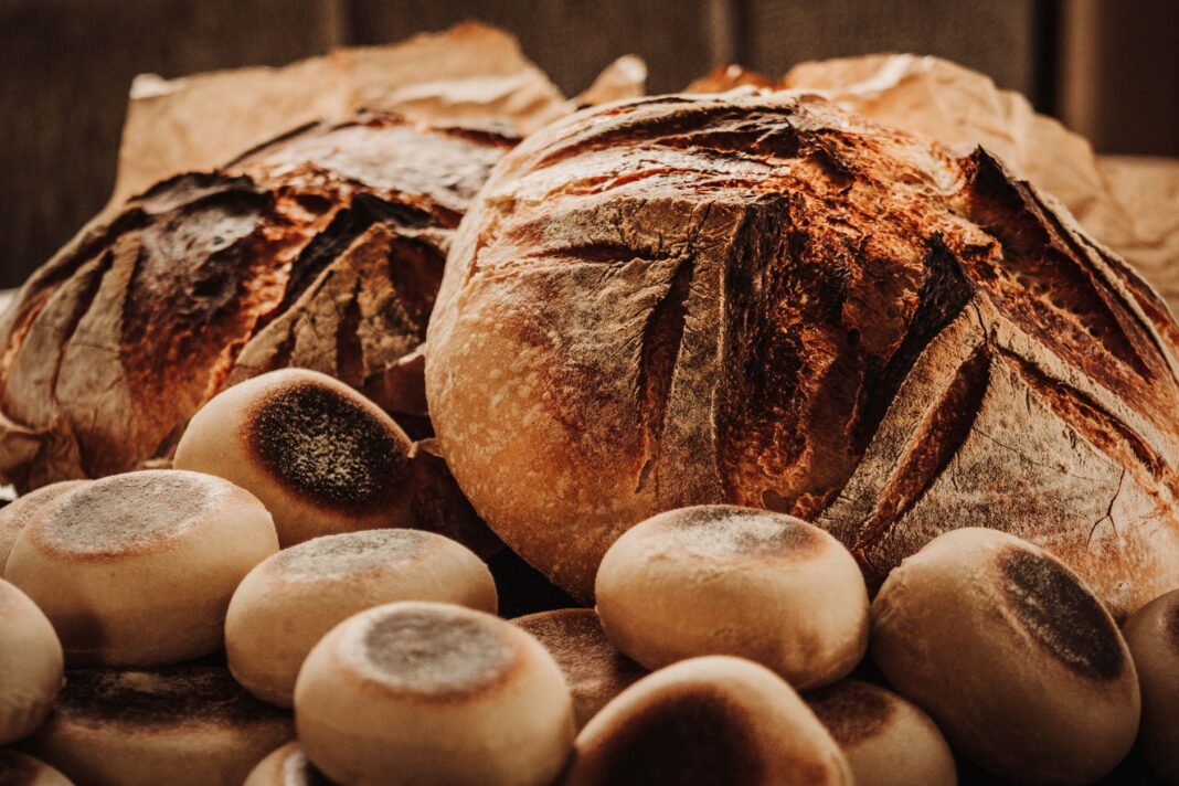 Świeżo upieczone bochenki i bułki chleba na zakwasie na rustykalnym stole Świeżo upieczone bochenki i bułki chleba na zakwasie na rustykalnym stole