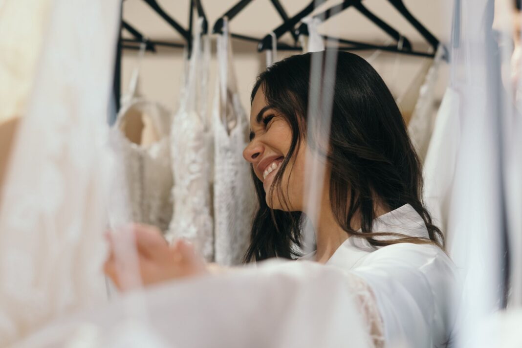 Uśmiechnięta panna młoda przymierza suknie ślubne w salonie bridal