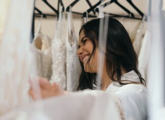 Uśmiechnięta panna młoda przymierza suknie ślubne w salonie bridal